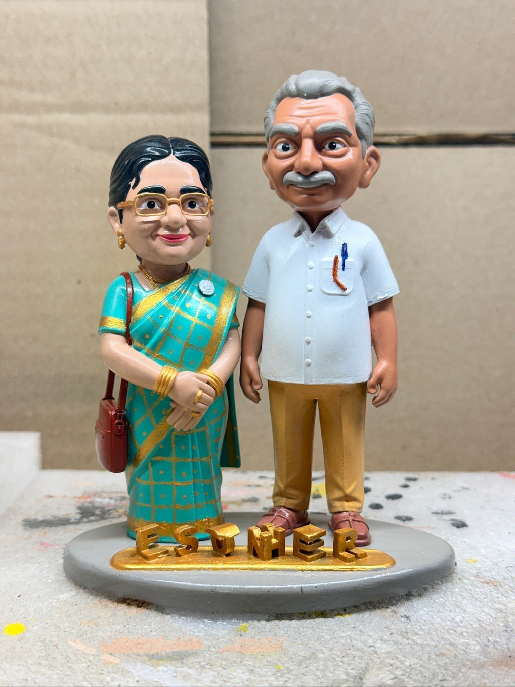 Anniversary figurine of an elderly couple in green saree and white shirt